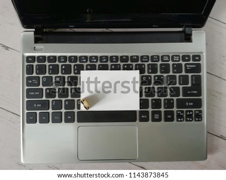 Padlock place on blank white card with laptop and white wooden table as background