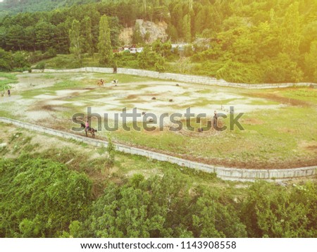 aerial unrecognizable sportsmen practice ride horse on the mountain field during summer day Royalty-Free Stock Photo #1143908558