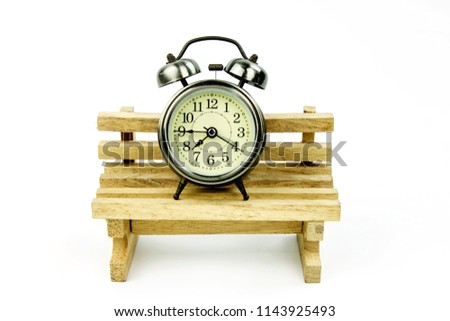 Retro alarm clock on a wooden chair and a white background.