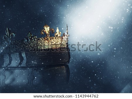 mysteriousand magical image of old crown and book over gothic black background. Medieval period concept