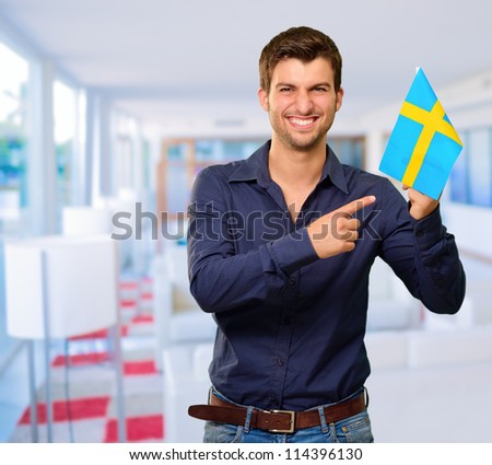A Young Man Holding A Flag Of Sweden, indoor