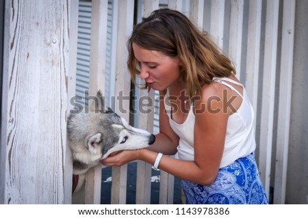 Beautiful Caucasian girl gently caressing a Siberian husky dog puppy. Girl owner caressing gently her husky pup. Love to animals, positive emotion, dog therapy training, pet therapy.
