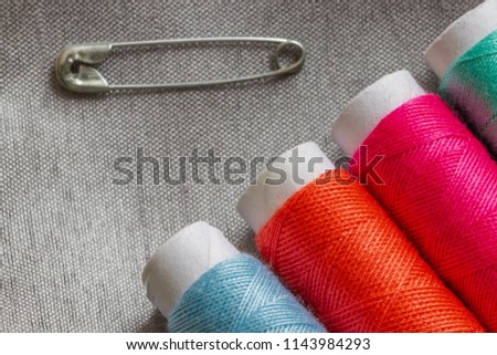 colorful sewing threads and safety pin on a gray background