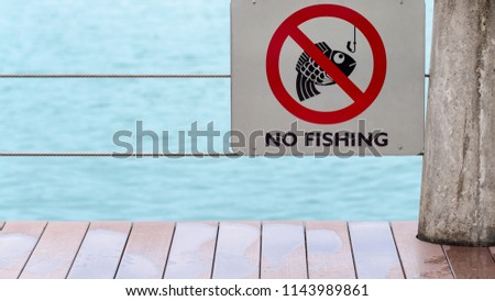 no fishing sign on fence by river or lake after rain with wet floor