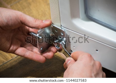 Man holds a wrench in his hand. the man is repairing the door. Hand tool.
