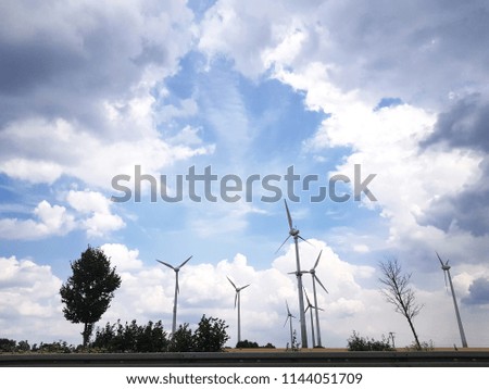 Wind turbines on sunny day with cloudy