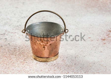Vintage copper bucket on concrete background. Copy space for text.