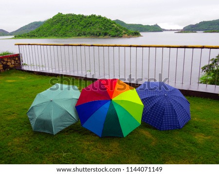    three colorful umbrellas in a garden of a lake island resort                            