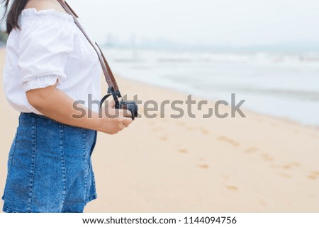 Woman holding a camera on the beach