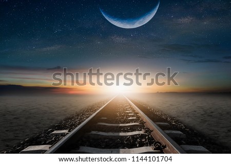The train cuts through the desert in the mornings, with a half-moon, to be beautifully laid. Royalty-Free Stock Photo #1144101704