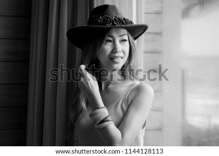 Portrait Beautiful asian woman wearing a hat looking out through the window.