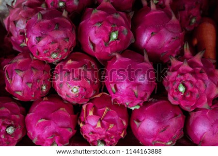 Pink dragonfruit pile on rustic market table. Ripe sweet dragon fruit. Colorful exotic fruit pile. Tropical fruit Pitahaya. Pink Pitaya for dessert or juice. Asian local market travel photo