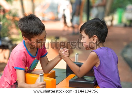 Two boys compete in a arm wrestling in the park in the summer