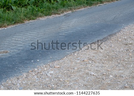 Asphalt way with gray stone road and stones on side