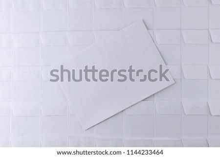 set of empty white envelopes lying in a row on a desk in the office, one envelope removed from the row and lying on the surface, short focus, toning