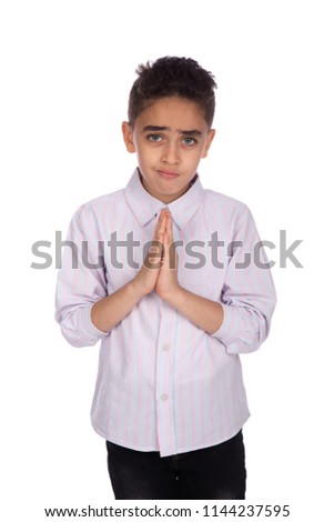 Close shot of a regret little boy wears a casual outfit, clasped his hands asking for forgiveness, isolated on white background
