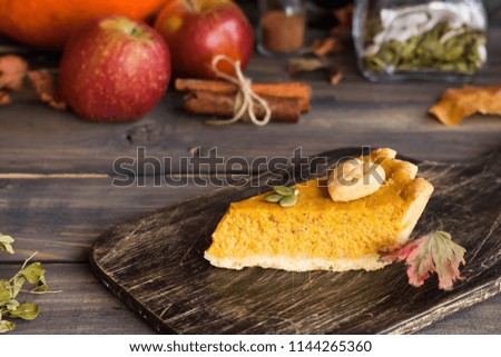 Traditional homemade American pumpkin pie with a decor of leaves and pumpkin seeds for a holiday