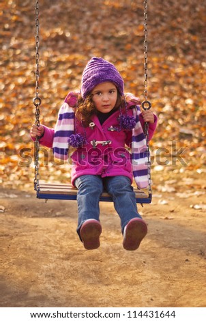 little cute  girl swinging  at the park in autumn