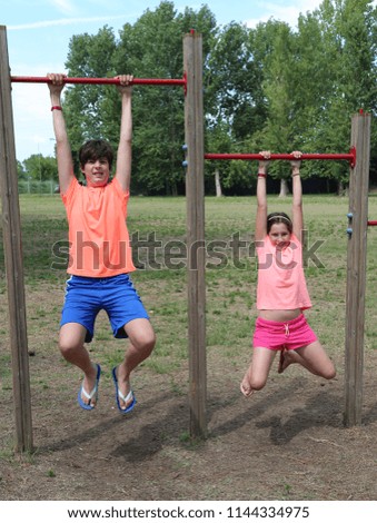 child and little girl hanging from the poles to do gymnastics in a holiday village