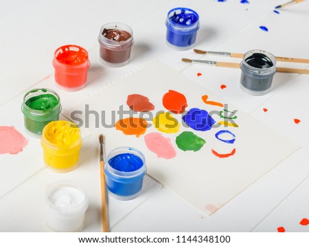 Multi-colored paint and brushes on a white table. Creative kit. Flat lay.