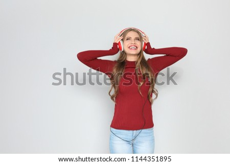 Young woman listening to Christmas music on color background