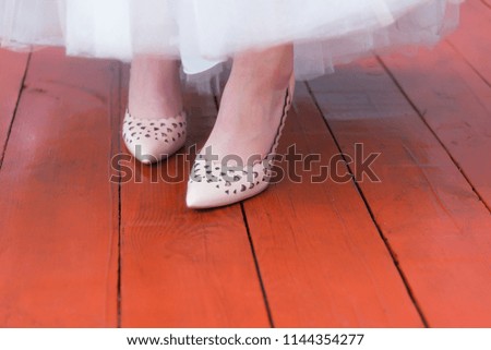 Bride shoes and wedding dress on a red wooden road.