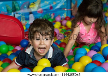 Happy children having fun at kids indoor play center. Kids playing with colorful balls in playground ball pool. Holiday, children's party, a games room