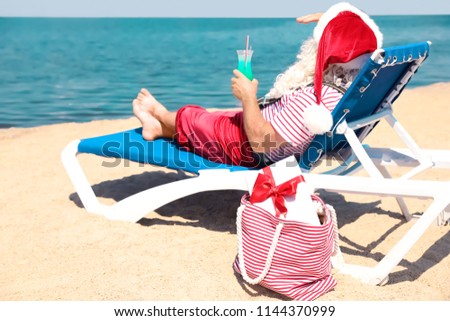 Authentic Santa Claus with cocktail resting on lounge chair at resort