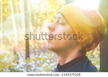 Young man with closed eyes close up in forest. Toned photo