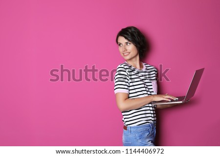 Young woman with modern laptop on color background