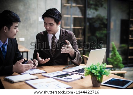 Image of two young asia businessmen using touchpad at meeting