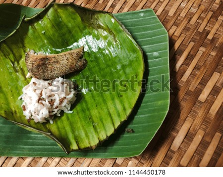 Fried fish with rice on the banana leaf.
