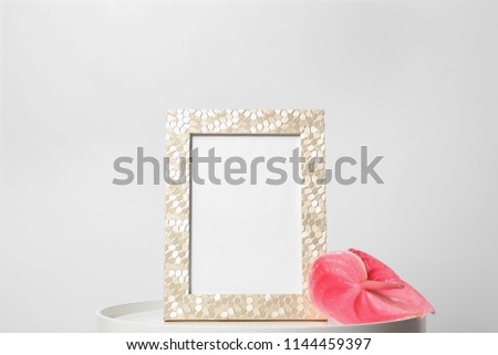 Blank frame and flower on table against white background. Mock up for design