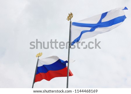 Tricolor Flag of Russia and Russian Navy Ensign, also Known as St. Andrews Flag Isolated on Empty Sky Background. Naval Flag and National Flag of the Russian Federation on Pole for Navy Day Parade. Royalty-Free Stock Photo #1144468169