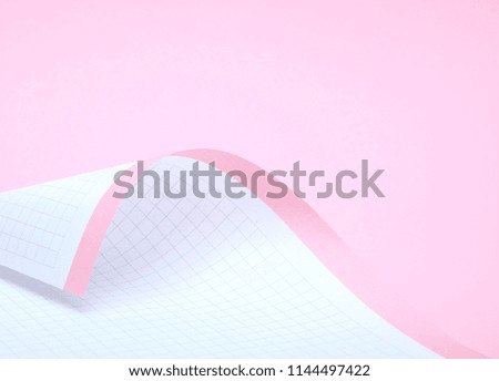 Pink paper, partially rolled up, close-up on a pink background.