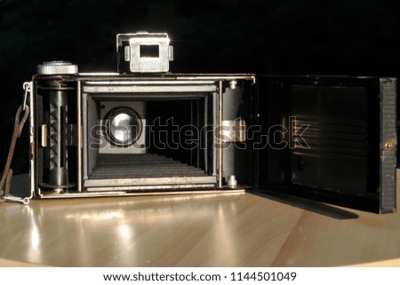 Old folding camera with an open back cover, internal view of the lens, camera bellows and spool for 120 film
