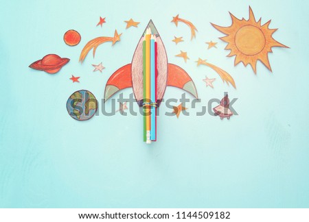 Back to school concept. rocket, space elements shapes cut from paper and painted over wooden blue background