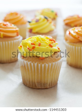 Cupcake with yellow icing and sprink?es vertical