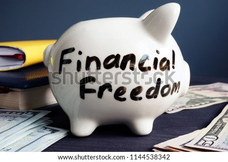 Financial freedom written on a side of piggy bank. Royalty-Free Stock Photo #1144538342