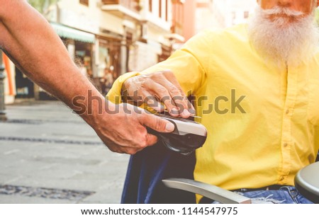 Male customer paying with contactless credit card with NFC technology - Waiter with a credit card reader machine at bar outdoor - New tech payment concept - Focus on hands