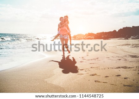 Mother and daughter running next the water on tropical beach - Mum playing with her kid in holiday vacation - Family lifestyle and love concept - Focus on bodies silhouettes