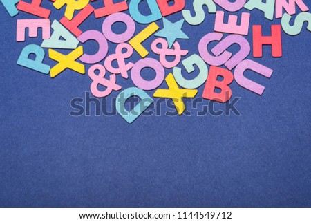 Mixed colorful English alphabets with copy space on blue background.