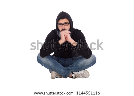 Handsome young man wearing a casual outfit and sitting on the floor crossed legs, putting his chin in his hand, isolated on white background