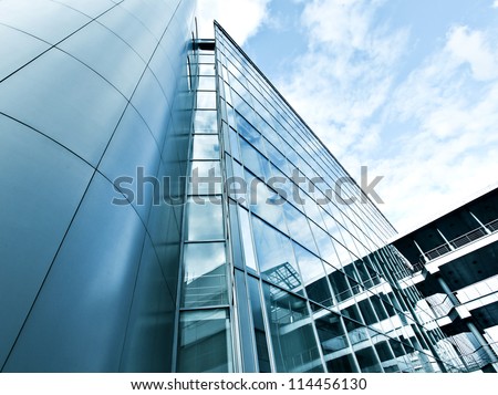 Perspective and underside angle view to textured background of modern glass building skyscrapers over blue cloudy sky Royalty-Free Stock Photo #114456130