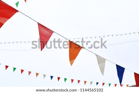 Colorful triangular Flags Hanging in the white sky outdoor.