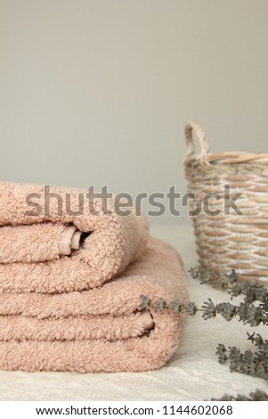 Clean bath towels near a wicker basket and lavendaer on a white blanket