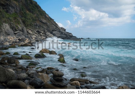 Natural beauty of the sea. A colorful seascape with dark rocks. The waves partially cover the stones. The picture with bright colors. 