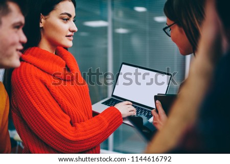 Successful group of graphic designers in casual wear discussing profile on website holding modern laptop with blank screen area for your internet content.Team of young people collaborating on app