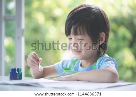 Cute Asian boy painting a picture