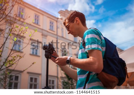 Portrait of happy young man, tourists with camera taking pictures of old city.